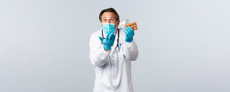 Covid19 防止病毒 保健工作者和接种疫苗概念 男性医生在医疗面具和手套上迷惑和困惑 抱怨药物不完善 诱人以及口罩装备管子防图片