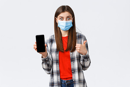 兴奋的年轻快乐女性推荐好应用 展示手机屏幕和拇指 戴医疗面具 在互联网上 您可以使用一个名为健康与技术的功能来保护自己员工广告潮图片