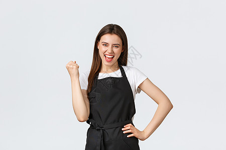 杂货店员工 小型企业和咖啡店的概念 身穿黑色围裙拳头泵的快乐女咖啡师欢欣鼓舞 庆祝伟大成就或成功图片
