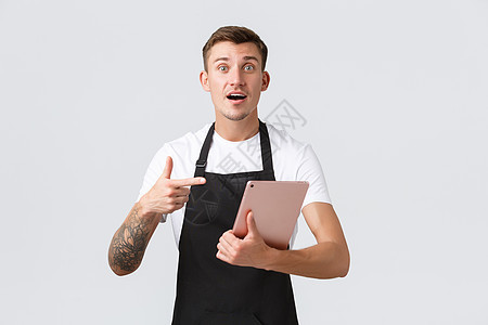小型企业 咖啡店和咖啡馆员工的概念 店里帅气 忧心忡忡的服务员或咖啡师指着数字平板电脑 询问订单问题 在柜台工作图片