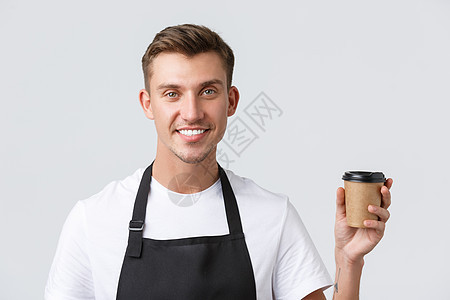 咖啡馆和餐馆 咖啡店老板和零售概念 友好英俊的咖啡师的特写镜头 服务员为客户提供外卖饮料 拿着纸杯 微笑着 白色背景图片