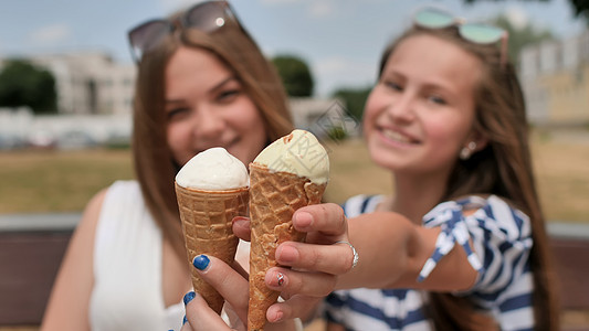有两个女孩在给观众送冰淇淋假期乐趣游客奶油街道微笑两个女孩甜点喜悦成人图片