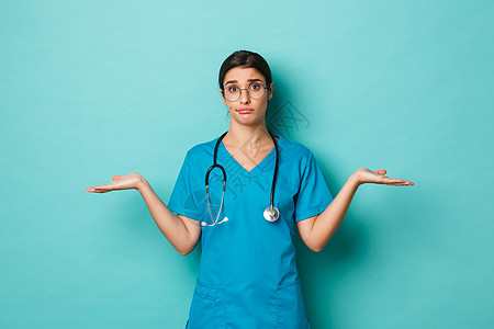 Corona病毒 大流行病和社会偏移概念 无精明的女医生身着洗涤剂和眼镜的形象 用散开的双手侧腰扭动 看不清 站在蓝色背景之上图片