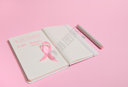 粉红丝带的顶视图 在打开的日记上 上面有提醒体检的铭文 10月1日 世界乳腺癌日 十月粉红日 世界癌症日 全国癌症幸存者说图片