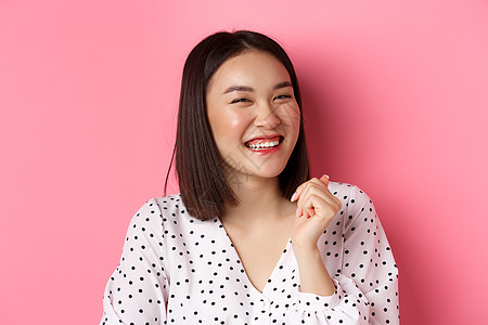 美和生活方式概念 近似于快乐的亚洲女性笑 看着欢乐 展现真正的情感 站在粉红背景之上冒充情绪促销广告女孩理发皮肤微笑横幅工作室图片