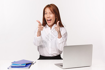 职业 工作和女企业家的概念 厚脸皮兴奋的亚洲办公室女士的特写照片保证一切顺利 鼓励您访问她的公司并使用服务 坐在笔记本电脑和笔记图片
