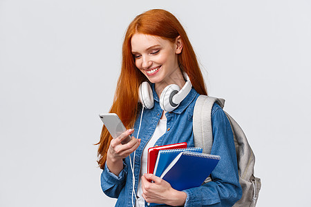青少年 大学和教育理念 迷人的红发女性 带耳机 背包和笔记本的大学生 回复女友信息 空气中的酷爱图片