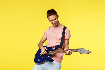 生活风格 休闲和青年概念 快乐 凉爽和时尚的亚洲男子在乐队中玩耍 享受电吉他打情骂俏 微笑热情 站立黄色背景技术商业音乐男朋友情图片