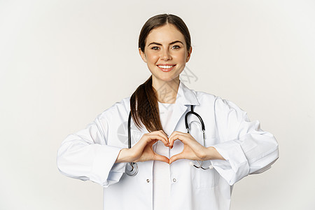 微笑的医生的画像 女医生表现出心脏迹象 小心翼翼地看着 爱她的病人 站在白色背景上图片