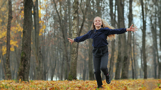 快乐的少女跑在秋天公园童年乐趣运动员女孩训练慢跑者城市锻炼跑步耳机图片