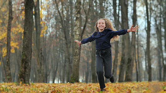 快乐的少女跑在秋天公园跑步女性橙子耳机短跑运动自由运动员喜悦晴天图片