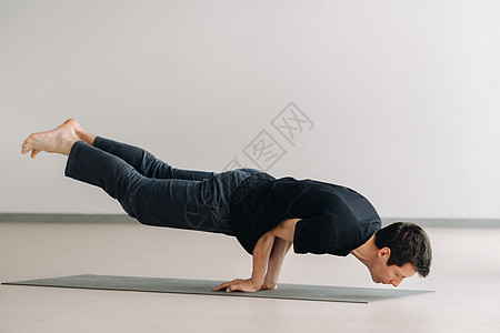 一个穿黑色T恤火车的男人 躺下在健身房做伸展身体成人护理姿态瑜伽运动装衣服运动肌肉闲暇图片