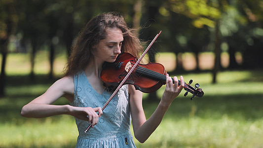 有个年轻女孩在公园里拉小提琴寂寞娱乐乐器艺术家歌手街道音乐家艺术派对女性图片