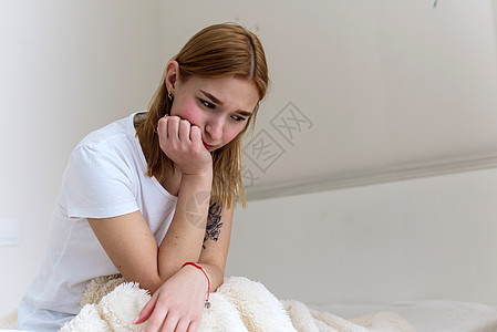 一位年轻女士坐在床上 将头抱在她的手中 感到悲伤 在家里沮丧 头痛苏醒情绪房间孤独卧室女孩焦虑沙发压力困惑图片
