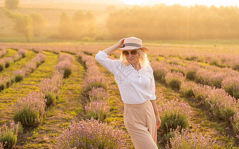 穿着草帽的金发年轻女旅行者 在熏衣草田里 围着紫色花朵时尚旅游薰衣草衬套帽子植物女性露肩卷曲场地图片
