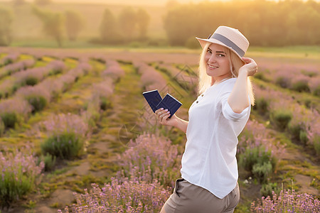 穿着草帽的金发年轻女旅行者 在熏衣草田里 围着紫色花朵女性旅游稻草蓝色时尚薰衣草衬衫牛仔女孩植物图片