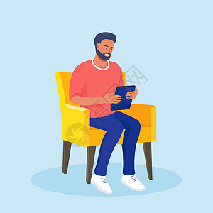 坐在椅子上并使用平板电脑的男子在互联网上冲浪或阅读一篇文章 商务人士在家网上聊天 社交媒体图片