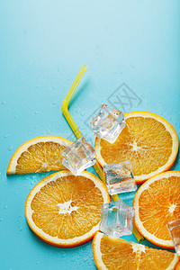 橙色切片和冰块 以鸡尾酒的形状 在蓝色背景上的稻草柠檬立方体玻璃营养酒精水果饮料食物果汁派对图片