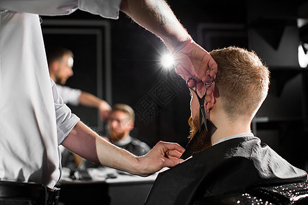 大师在理发店剪头发和胡子 美发师用剪刀和金属梳子做发型男人胡须客户男性发型师理发服务修饰职业工作图片
