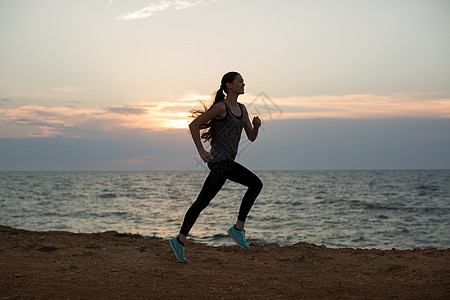 在一个惊人的日落中 一个年轻女孩在海滨上奔跑的休眠图片