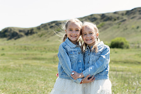 拥抱大自然两个双姐妹的肖像 在大自然中的草地中拥抱快乐兄弟小孩子跑步童年朋友姐姐幸福乐趣喜悦背景
