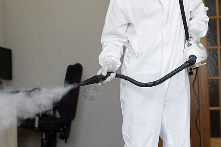穿着防护服的消毒员在家中进行消毒 针对 COVID-19 冠状病毒的专业消毒 在工业中防止化学中毒的服装图片