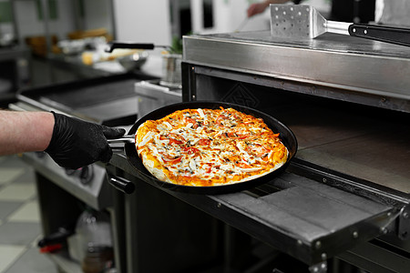 比萨厨师在烤箱里放披萨 在餐厅厨房的烤箱里烤图片