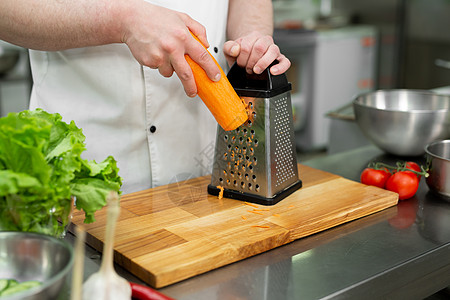 厨师用蔬菜背景的胡萝卜做沙拉图片