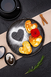 巧克力蛋糕煎饼 以心脏的形状 蜂蜜和果酱在黑色板块上图片