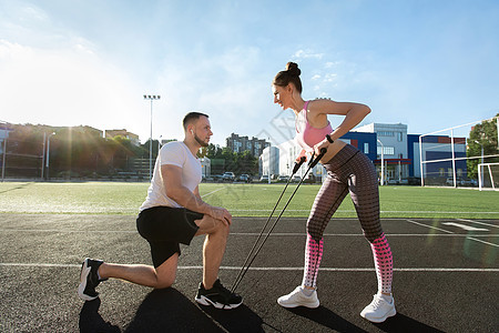 夏季在体育场培训青年运动者 一名妇女与扩音员一起锻炼 一名男子帮助她工作图片