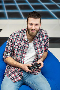 一个快乐兴奋的年轻人坐在椅子上 手里拿着控制器 玩电子游戏 玩得很开心 VR 控制台游戏手柄幸福娱乐成人安慰视频活动男人沙发竞赛图片