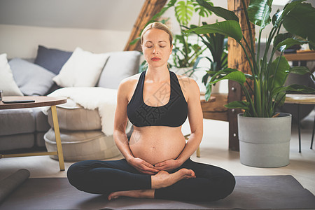 训练瑜伽的年轻美丽的孕妇 爱抚她的腹部 年轻快乐期待放松 想着她的孩子 享受她未来的生活 孕产 怀孕 瑜伽概念母亲母性女士家庭身图片