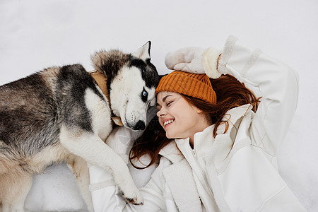 快乐的年轻女子冬衣 在雪中新鲜空气中走狗图片