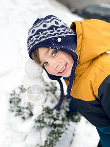 五岁快乐的男孩 冬天下雪男生天气娱乐雪人闲暇帽子公园衣服情绪微笑图片