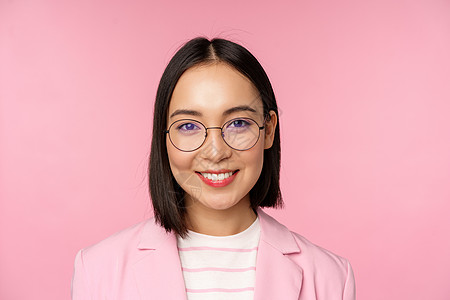 戴眼镜的女人亚洲企业女性特写 戴眼镜的职业女商务人士 面带微笑 对着镜头自信满满 粉红色背景职场标识商务购物经理大学工作广告企业家办公室背景