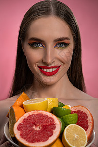 美丽的时装模特女孩 妆容漂亮 嘴唇红润 头发长而健康 手里拿着五颜六色的鲜切柑橘类水果 酸橙 橙子 柠檬 葡萄柚 时尚理念图片