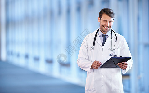 医院检查准备作出诊断 一位快乐的年轻医生拿着病人图表站在医院走廊里的画像背景