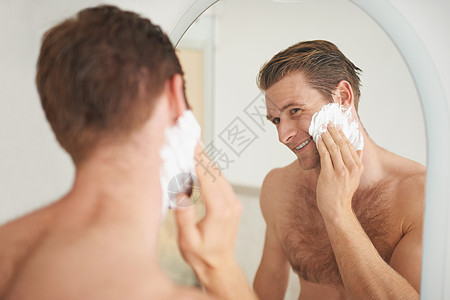 一个英俊的年轻人在镜子前 将剃须膏涂到脸上了 - 是的图片