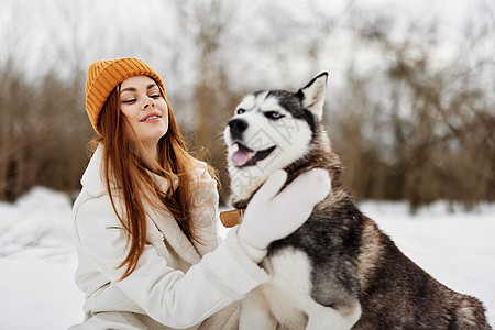 在雪雪中快乐的女人 和狗玩乐的友情 生活风格财产毯子羊毛格子住房剧院魔法女士牛仔裤友谊图片