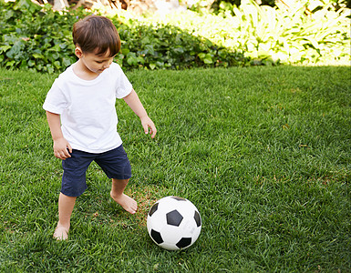 后院足球 一个甜美的小男孩在后院里踢足球青年孩子们玩家乐趣娱乐运动运动装赤脚男生花园图片