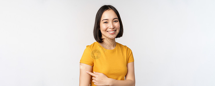 Covid19疫苗接种运动 笑笑的亚洲女孩指着她的肩膀上助力 建议从阴性冠状病毒 白本子获得疫苗技术大学女朋友衬衫广告企业家互联图片