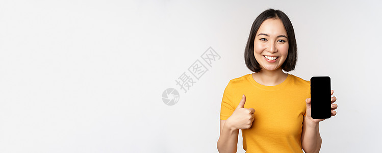 技术和人的概念 微笑的年轻女性竖起大拇指 智能手机屏幕 手机应用程序界面 站在白色背景下送货购物女士女朋友展示横幅商业命令细胞工图片