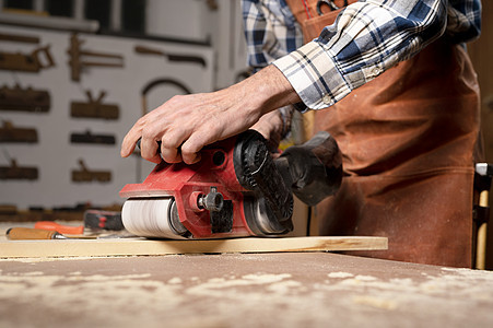 在木板项目或木工木工车间 木匠用带式砂光机打磨木材作坊木匠铺灰尘抛光男人工人家具磨床木头工作图片