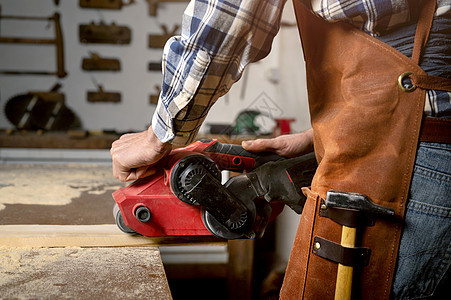 在木板项目或木工木工车间 木匠用带式砂光机打磨木材职业工具男性磨床木匠铺男人木头家具木制品工艺图片