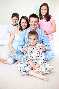 星期六早上早起的人 一个可爱的小男孩的画像 他的家人快乐地坐在他身后的床上图片