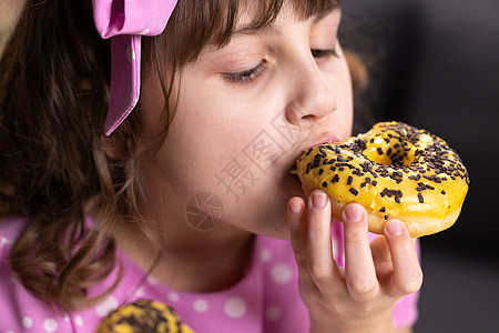 年轻饥饿的女孩吃甜甜圈的画像 女性的嘴咬了一条面包 特写女人吃甜甜圈 美味 甜美 在家庭背景下爱吃甜食图片