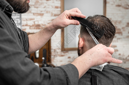 理发师用剪刀剪头发给一个英俊的年轻人顾客发型师发型理发成人造型师客户男性商业理发店图片