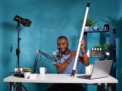 Vlog 评论员 展示在沃布工作室用笔记本电脑坐在办公桌旁的rgb管视频光灯背景图片