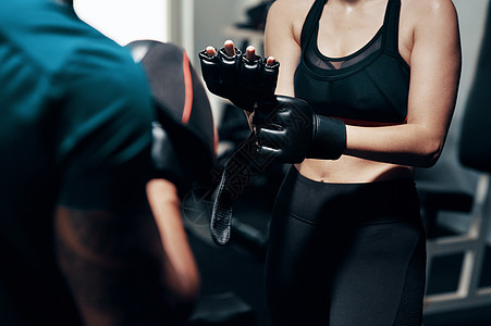 在挥拳之前确保你受到良好保护 一位面目全非的女运动员在健身房与她的私人教练一起锻炼时戴上防护手套的镜头图片