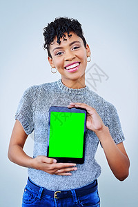 有个有魅力的年轻女人在蓝色背景下拿着数字平板电脑 她画的一幅肖像图片
